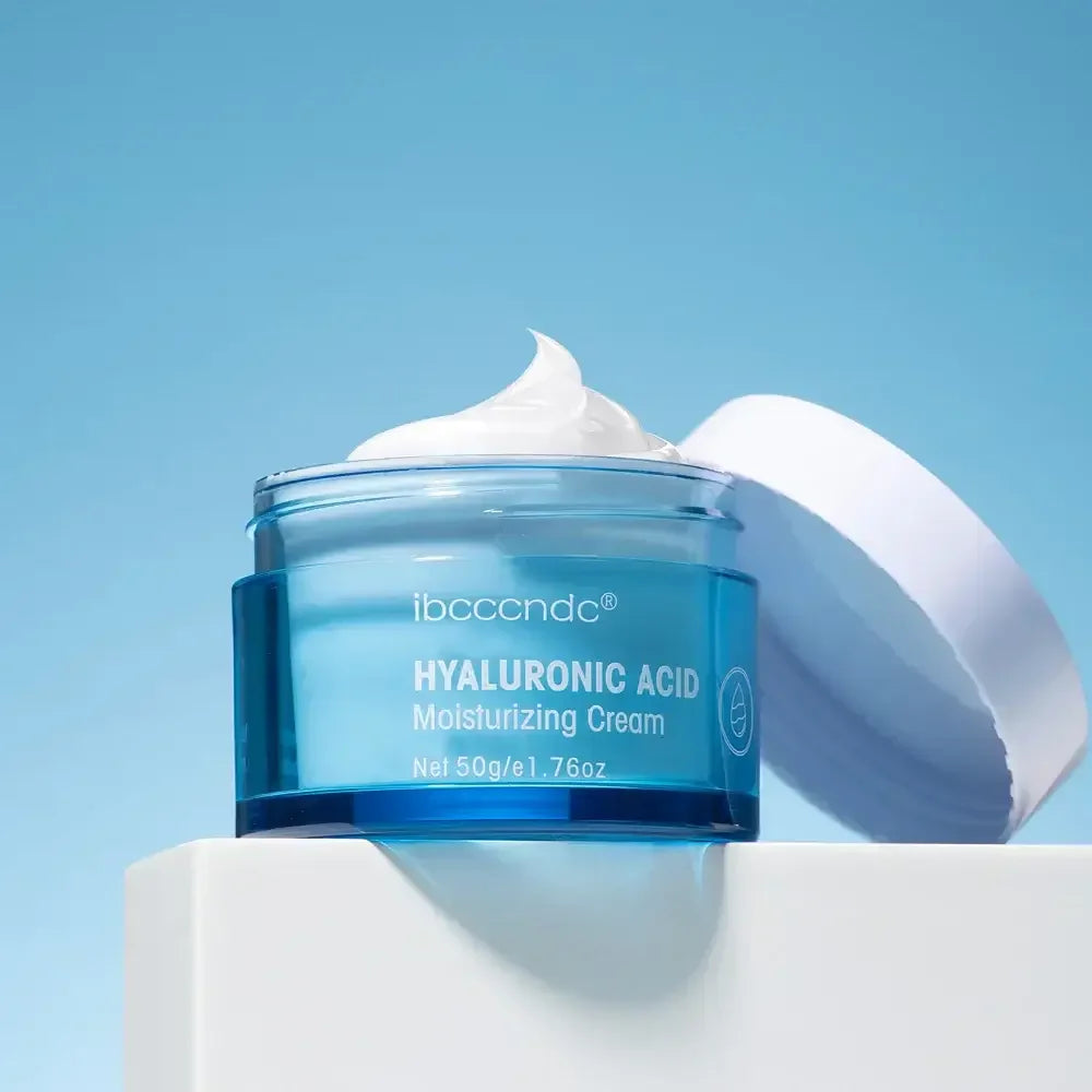 Open jar of hyaluronic acid moisturizing cream with white lid on white surface against blue background