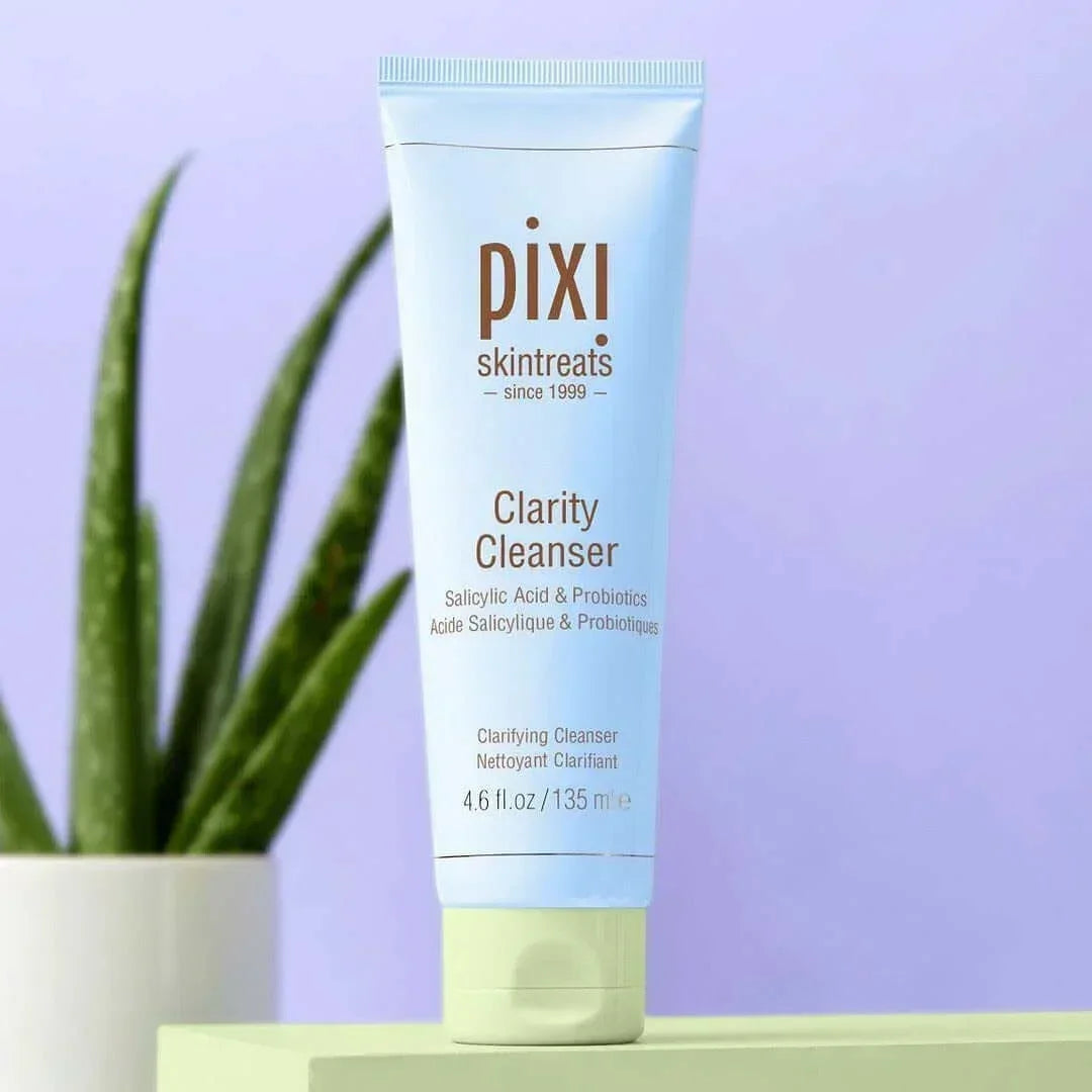 Pixi Clarity Cleanser tube with salicylic acid and probiotics on green surface, aloe plant background