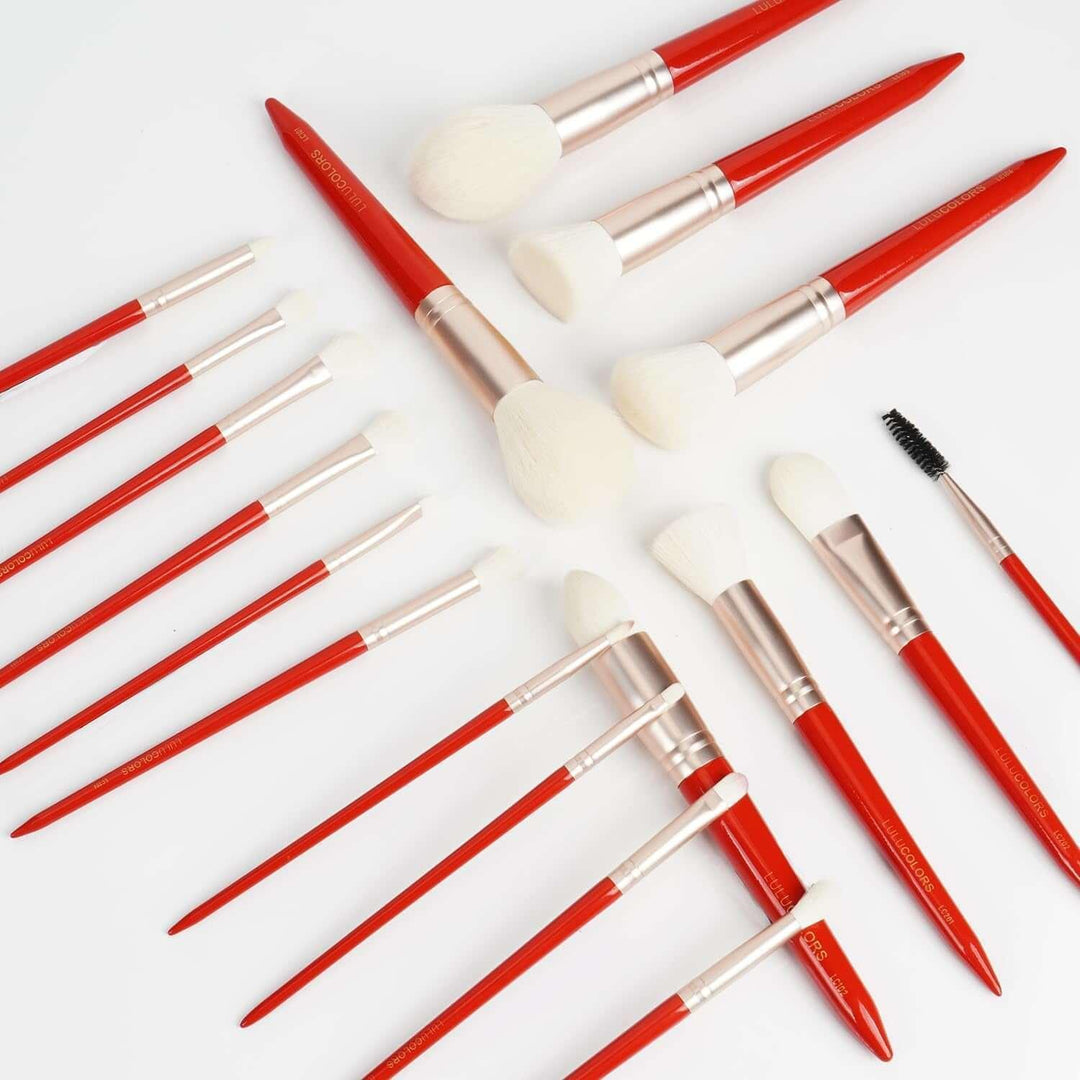 Collection of red-handled makeup brushes with white bristles on white background