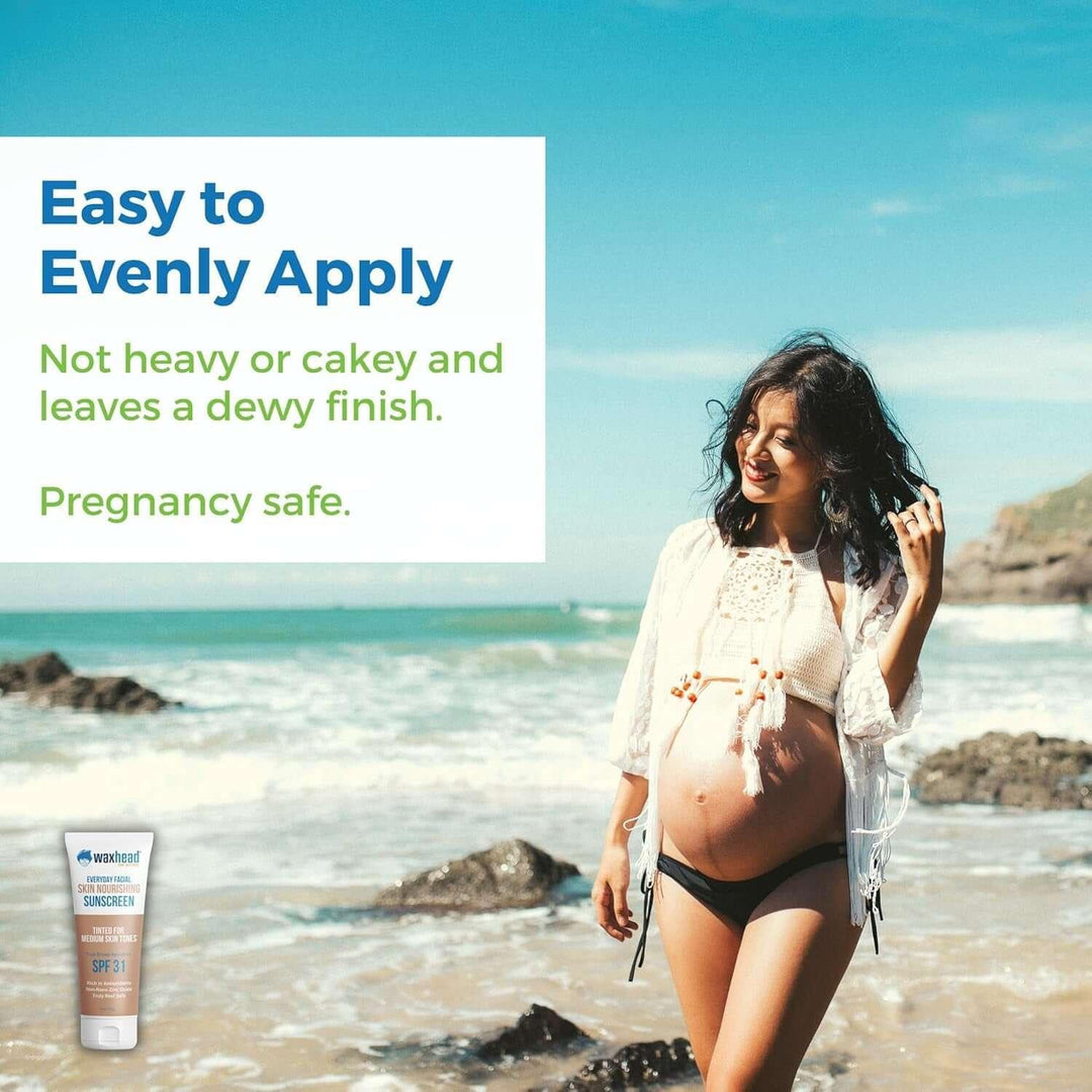 Pregnant woman on beach in sun hat and swimwear promoting pregnancy safe facial sunscreen with dewy finish