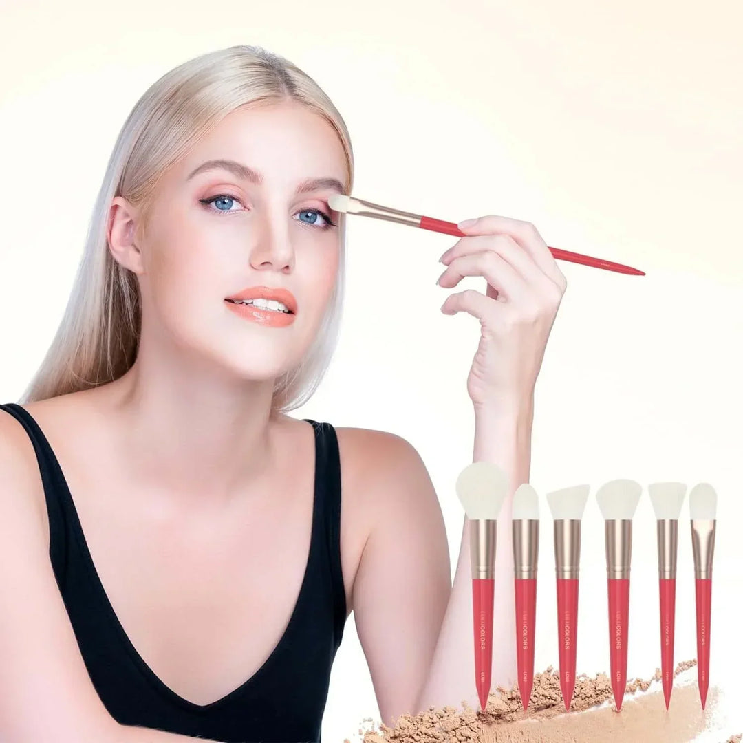 Blonde woman applying eyeshadow with red-handled makeup brush set on white background