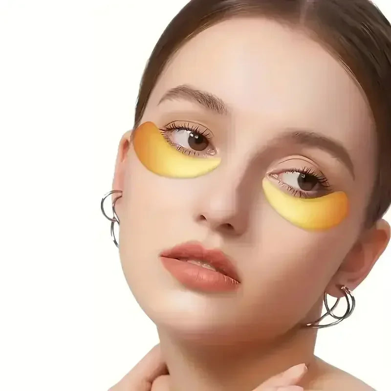 Close-up of woman wearing golden under-eye patches and silver hoop earrings on white background