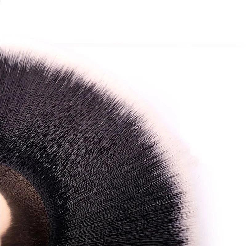 Close-up of soft, dense black makeup brush bristles on white background