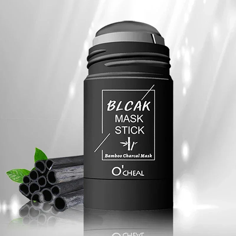 Black bamboo charcoal mask stick with green leaves and bamboo charcoal sticks on reflective surface