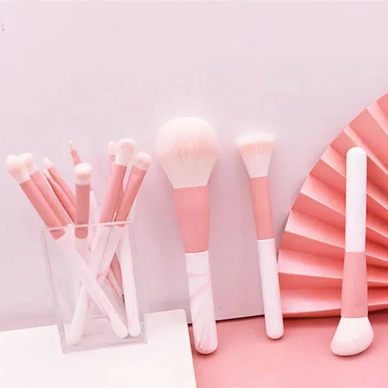 Set of pastel pink and white makeup brushes with soft bristles on light pink background