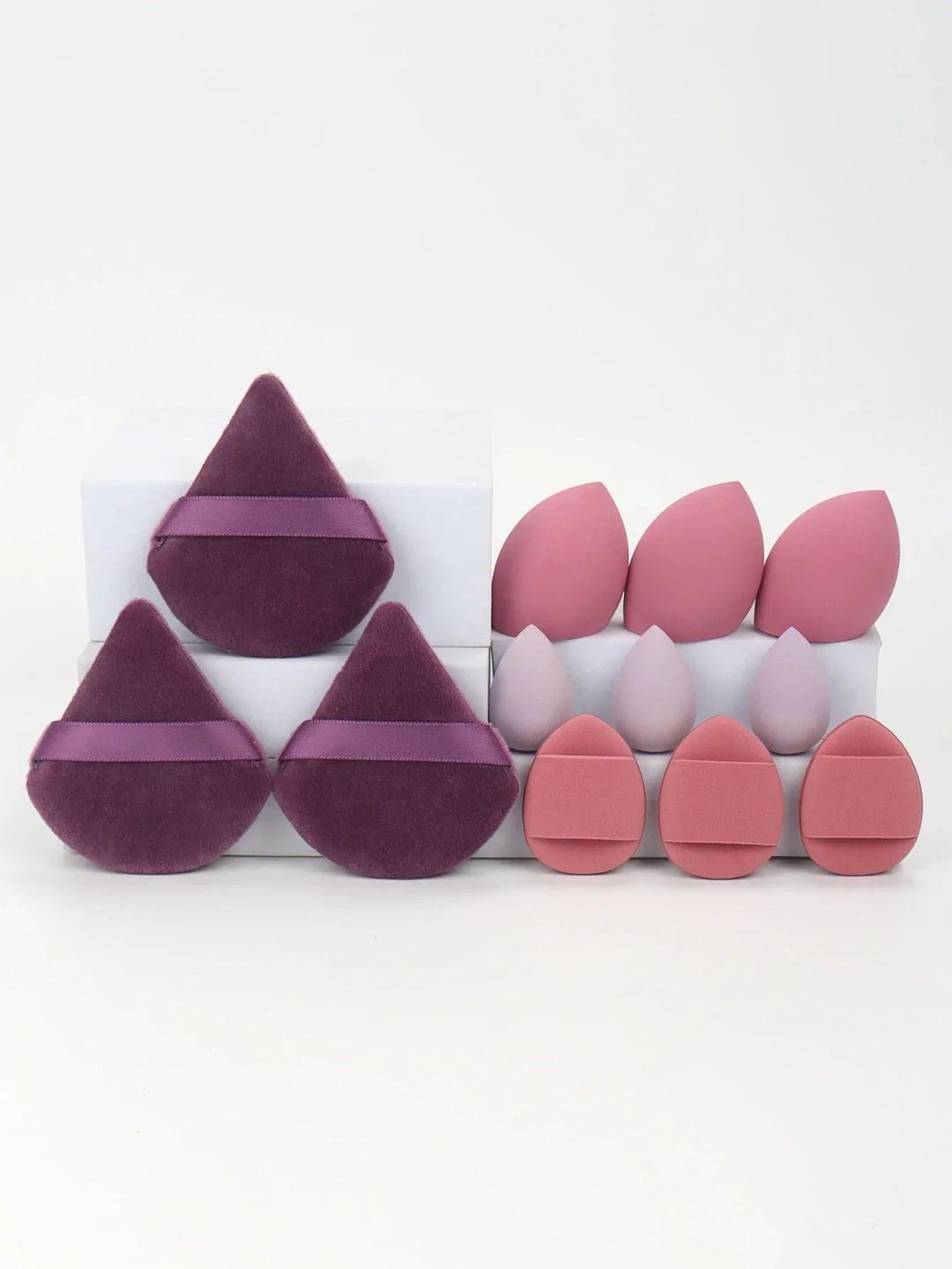 Set of purple velvet and pink makeup sponges in various shapes on white blocks