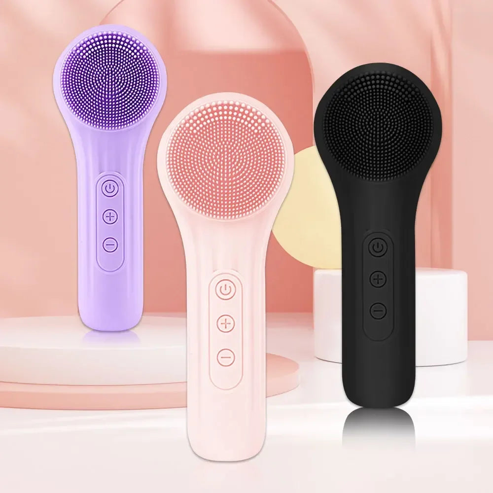 Three silicone electric facial cleansing brushes in purple, pink, and black on a soft peach background