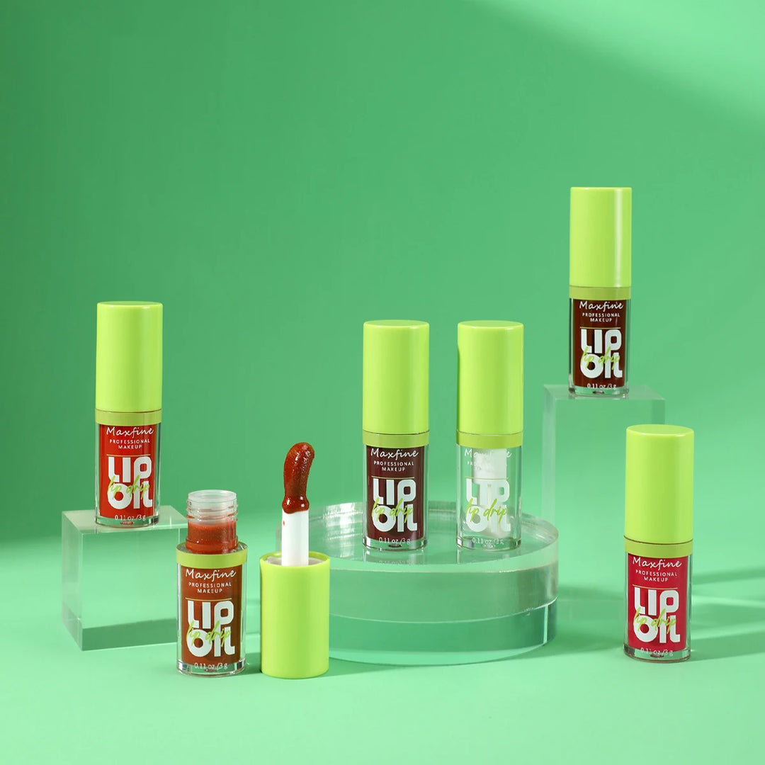 Maxfine professional makeup lip oil bottles with yellow caps on green background