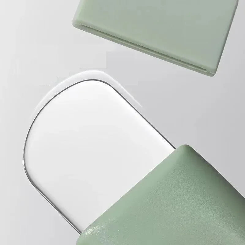 Transparent glass tray with rounded edges partially covered by a matte green cover on gray background