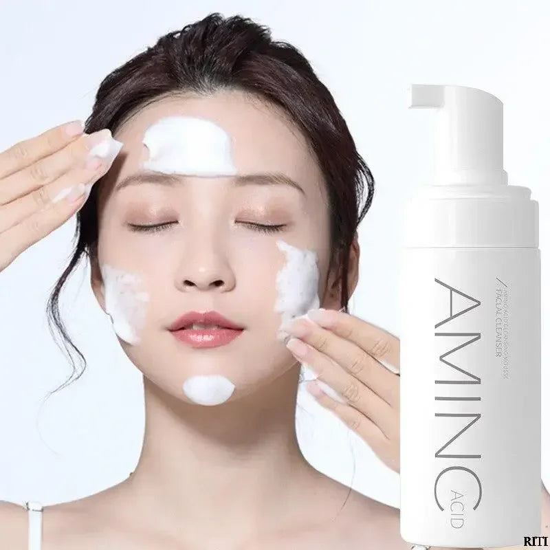 Woman applying foaming facial cleanser with Amino Acid label on white pump bottle