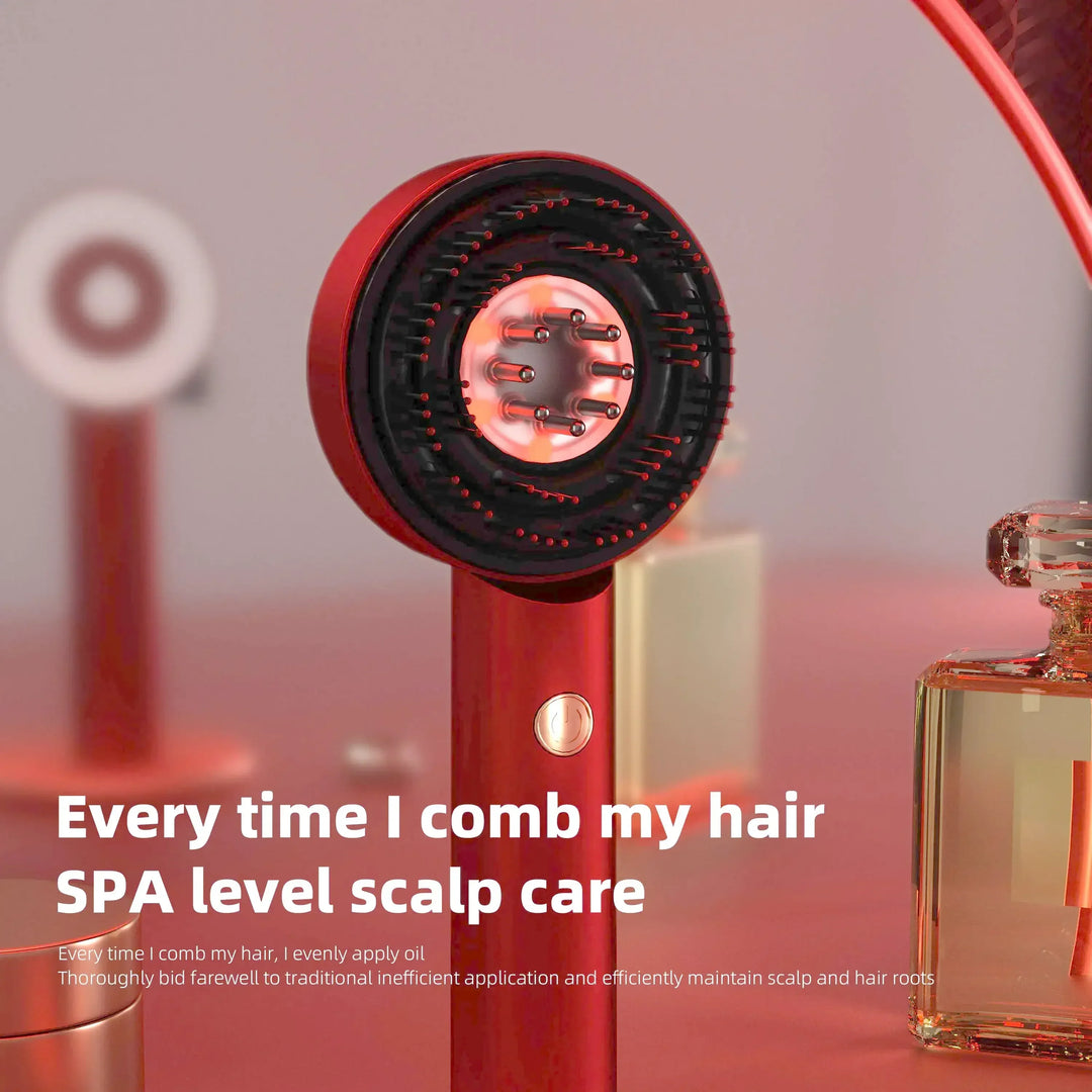 Red electric scalp care massager with brush pins on a pink surface near perfume bottles