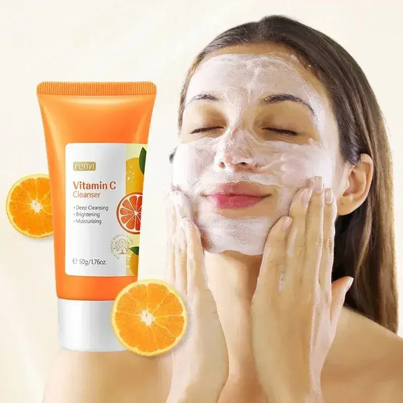 Woman applying foaming Vitamin C cleanser with orange slices and product tube for brightening skin