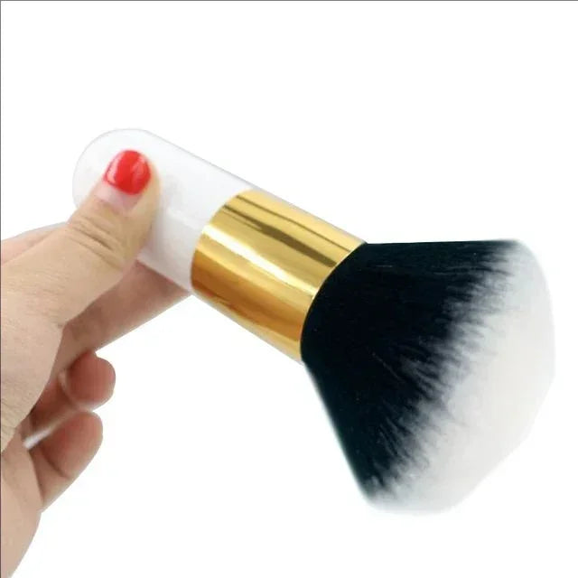 Hand holding a black and white dense makeup brush with white and gold handle on a white background
