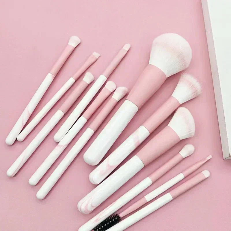 Set of pink and white makeup brushes with various sizes and shapes on a pink background