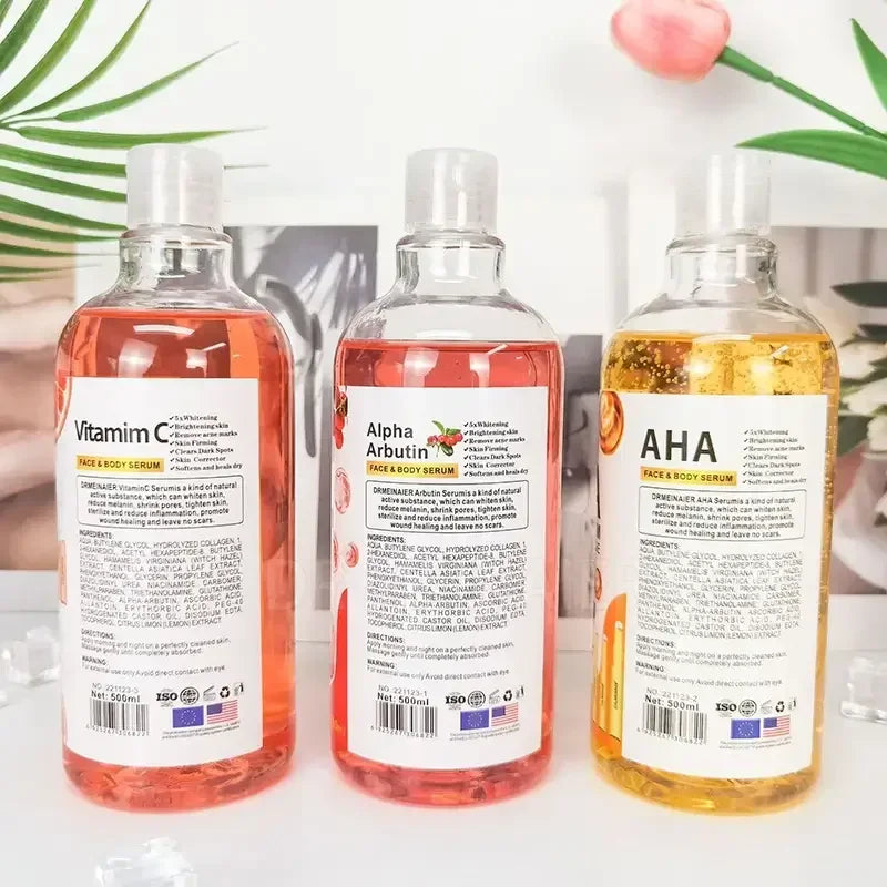 Vitamin C, Alpha Arbutin, and AHA face and body serums in clear bottles with botanical background