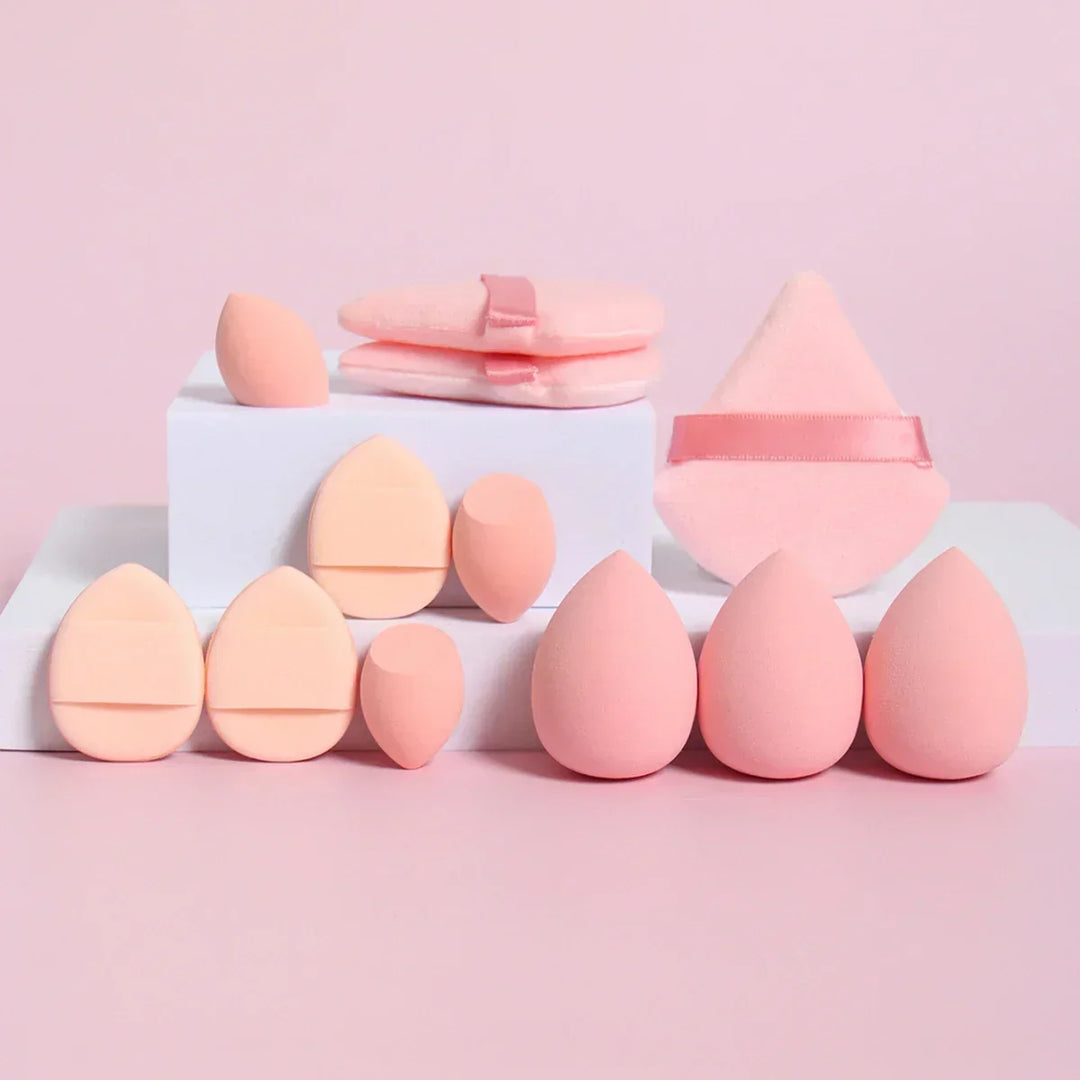 Various pink makeup sponges and powder puffs arranged on white blocks with pink background