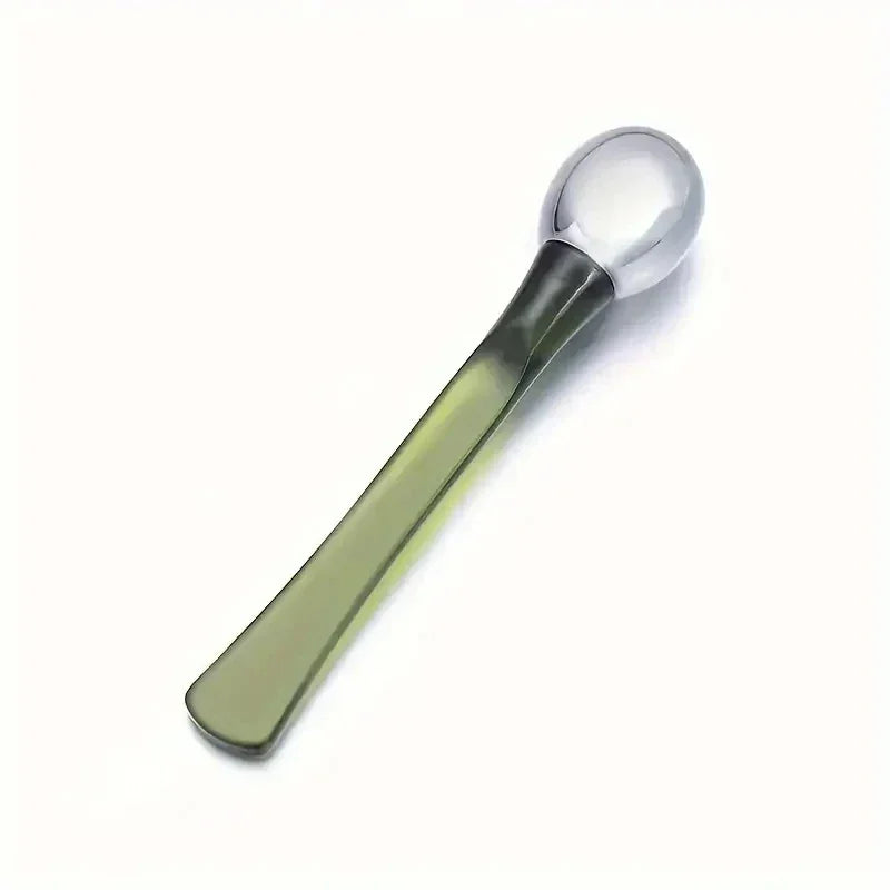 Transparent glass spoon with a rounded handle on white background