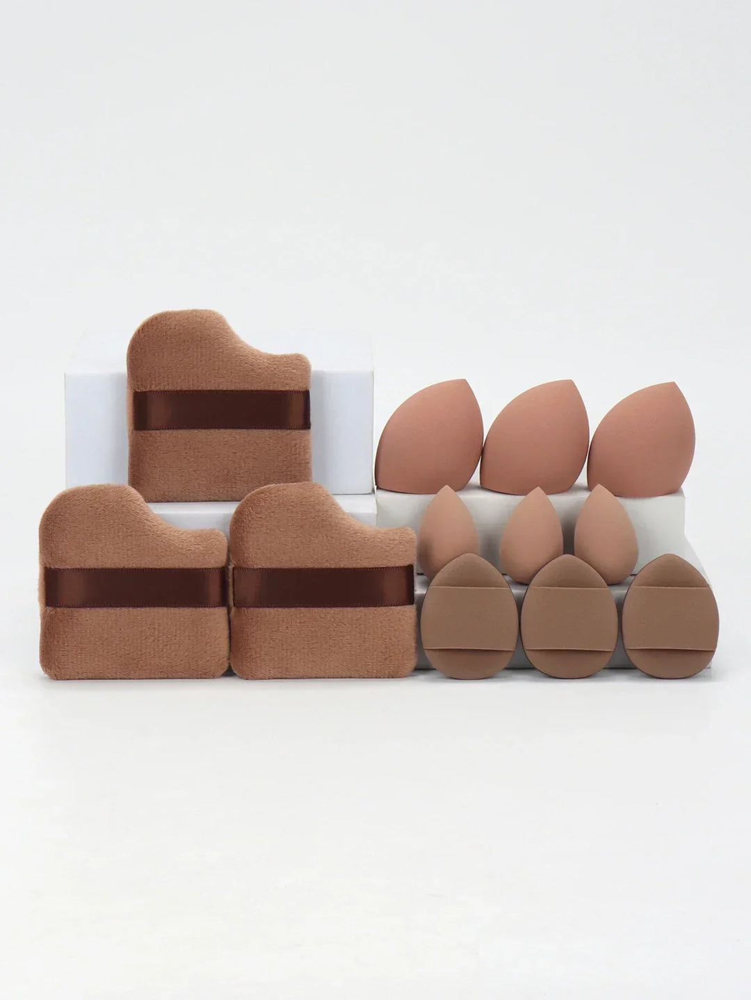 Various brown makeup sponges and powder puffs arranged on white surface with clean background