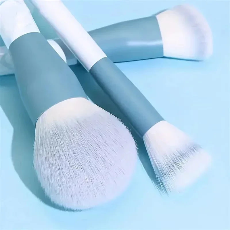 Set of makeup brushes with soft white bristles and blue handles on light blue background